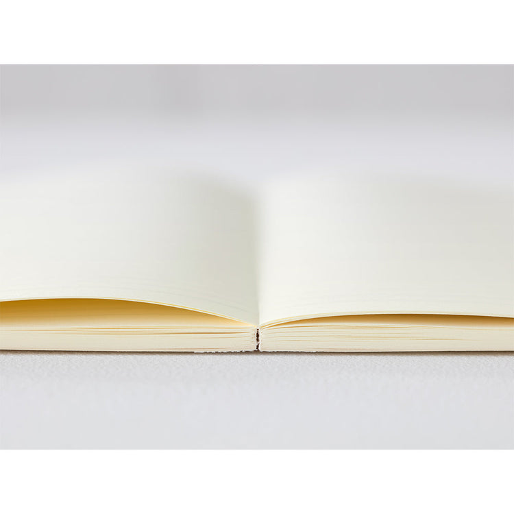 A6 MD Notebook Diary 2026 with a minimalist cream glassine paper cover, featuring monthly block schedule pages, weekly planning sections divided into eight segments, and blank memo pages. Thread-bound for 180-degree flat opening, complete with a slim bookmark string and index label.