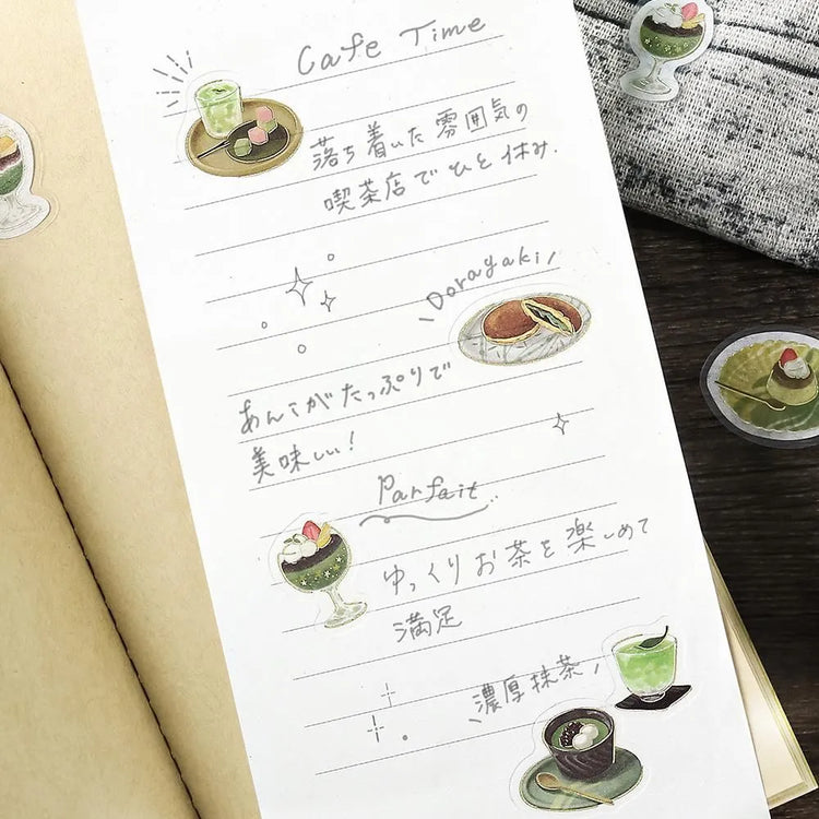 Green matcha-themed café flake sticker sheet with illustrated desserts, tea bowls and small plates accented with foil.