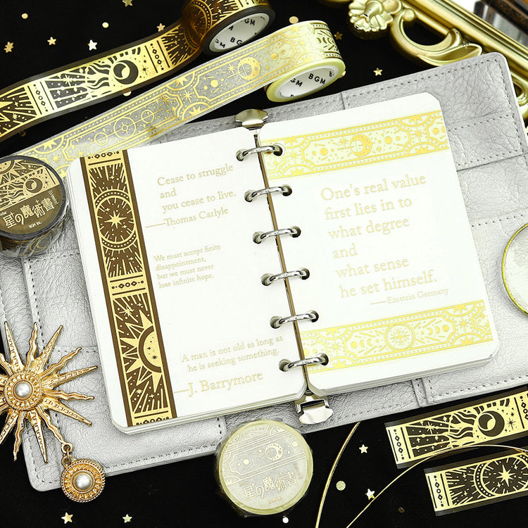 A roll of gold-toned washi tape with celestial suns, moons, and foil accents from the Grimoire of Stars Holy edition.