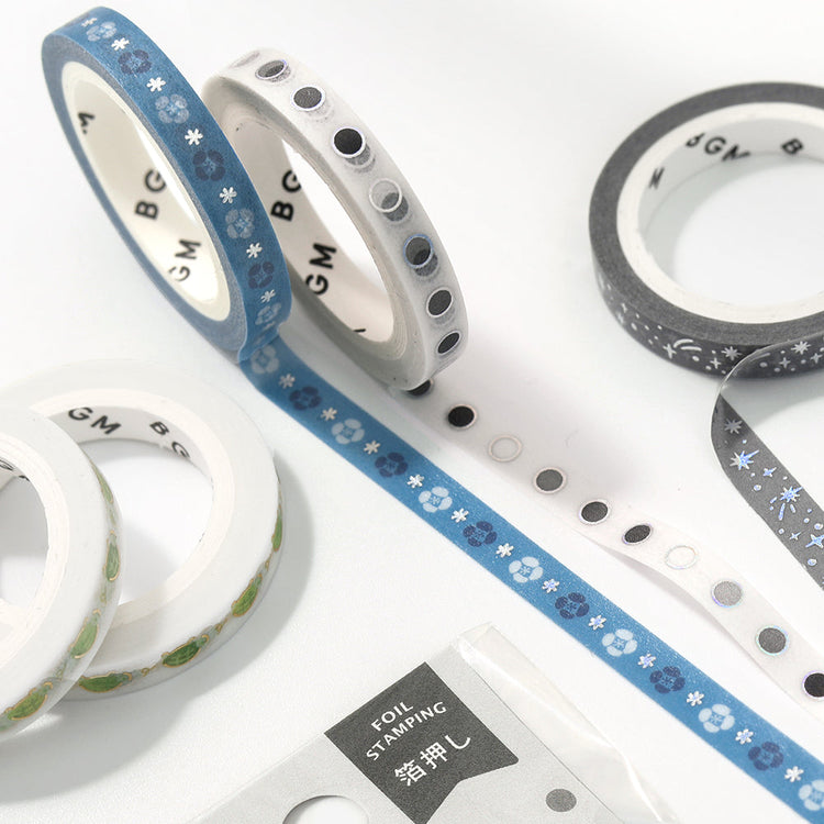 A slim 5mm wide washi tape roll with metallic foil round patterns, perfect for decorating planners, journals, and crafts with a clean modern touch.