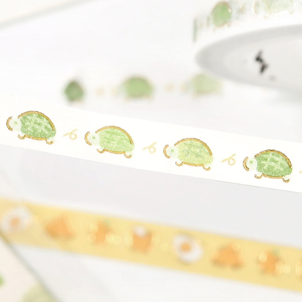 A slim roll of washi tape decorated with a repeating pattern of turtles running, accented with metallic foil highlights—ideal for planners, journals, and scrapbook decoration.