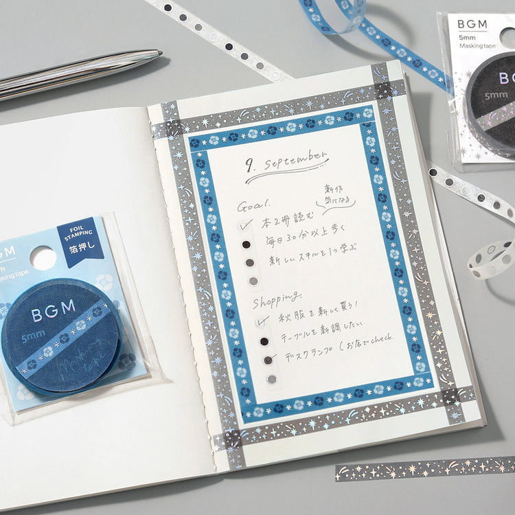 A slim 5mm washi tape roll with star patterns highlighted in metallic foil, designed for journaling, scrapbooking, and decorative accents.