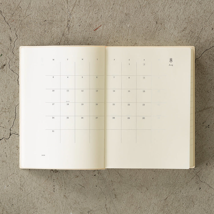 MD Notebook Diary (A5) 1 Day 1 Page 2026 with a minimalist PVC cover, year-stamped spine, and index tabs for each month. The diary is open to show a clean daily page layout on premium MD PAPER, ideal for journaling or planning.