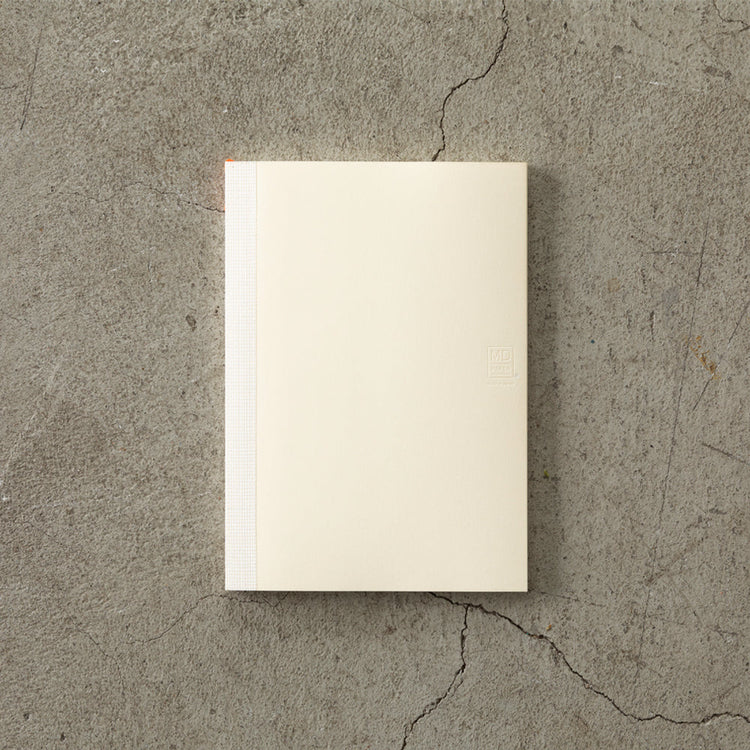 MD Notebook Diary (A5) Thin 2026 – A slim, thread-bound diary with a minimalist cream cover and glassine paper wrap, featuring monthly schedule pages, 5mm grid memo pages, and a bookmark string. Compact and lightweight, designed for portability and everyday use.