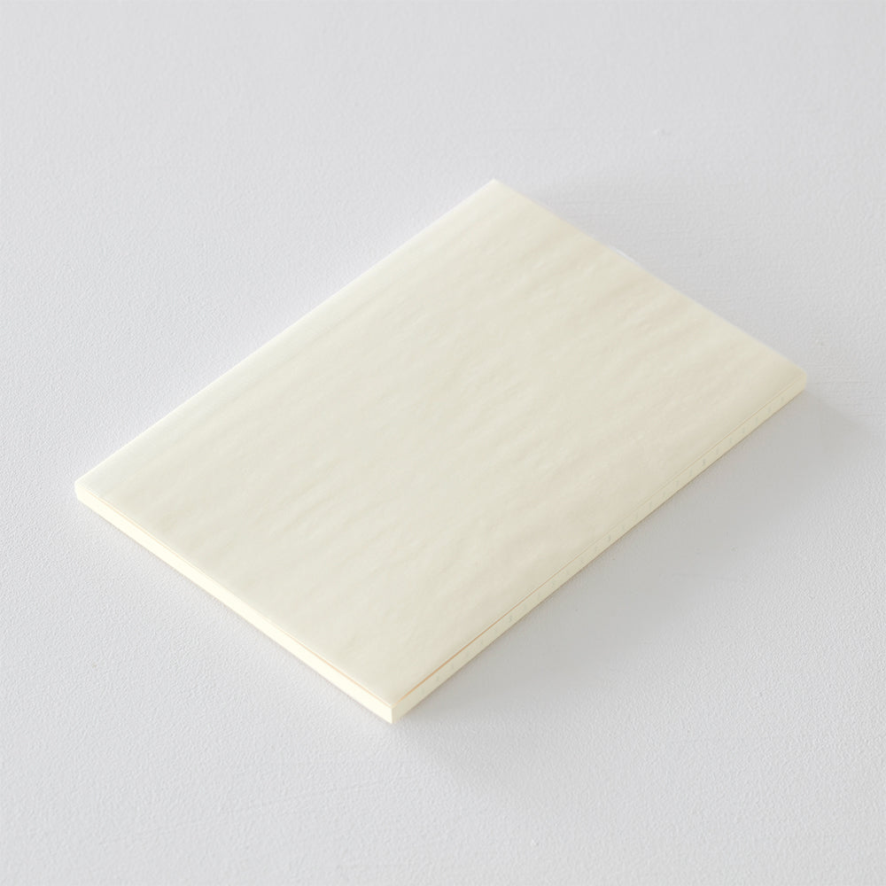 MD Notebook Diary (A5) Thin 2026 – A slim, thread-bound diary with a minimalist cream cover and glassine paper wrap, featuring monthly schedule pages, 5mm grid memo pages, and a bookmark string. Compact and lightweight, designed for portability and everyday use.