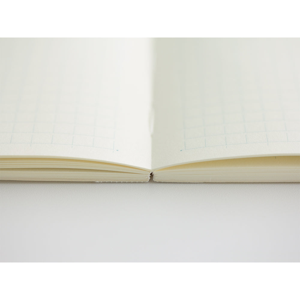 MD Notebook Diary (A5) Thin 2026 – A slim, thread-bound diary with a minimalist cream cover and glassine paper wrap, featuring monthly schedule pages, 5mm grid memo pages, and a bookmark string. Compact and lightweight, designed for portability and everyday use.