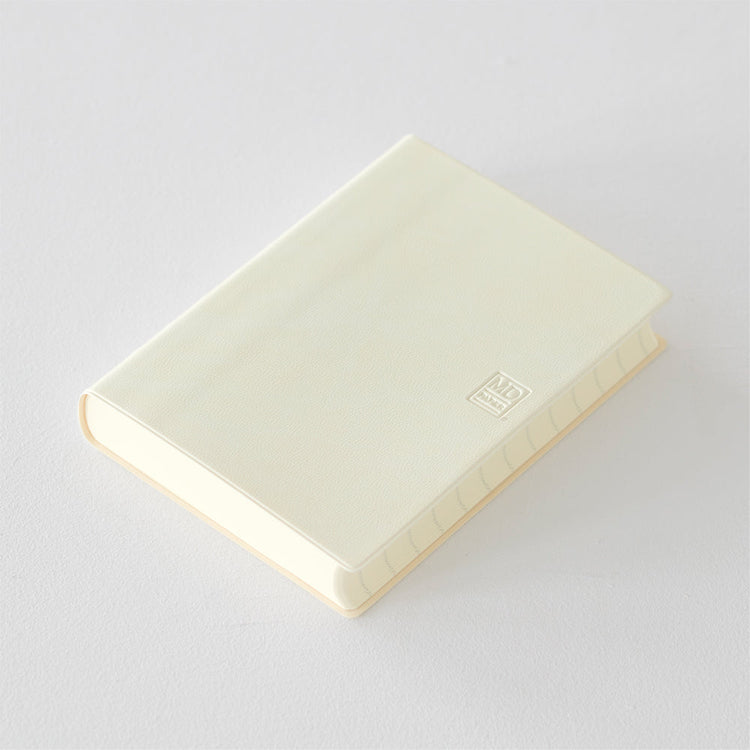 MD Notebook Diary (A6) 1 Day 1 Page 2026 with a minimalist PVC cover, featuring a year stamp on the spine, two bookmark strings, and monthly index tabs. The diary is open to reveal its premium MD PAPER with a clean, spacious layout for daily entries.
