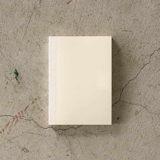 A6 MD Notebook Diary 2026 with a minimalist cream glassine paper cover, featuring monthly block schedule pages, weekly planning sections divided into eight segments, and blank memo pages. Thread-bound for 180-degree flat opening, complete with a slim bookmark string and index label.