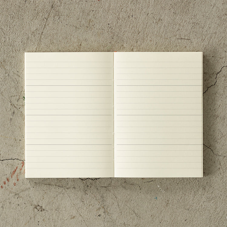 A6 MD Notebook Diary 2026 with a minimalist cream glassine paper cover, featuring monthly block schedule pages, weekly planning sections divided into eight segments, and blank memo pages. Thread-bound for 180-degree flat opening, complete with a slim bookmark string and index label.