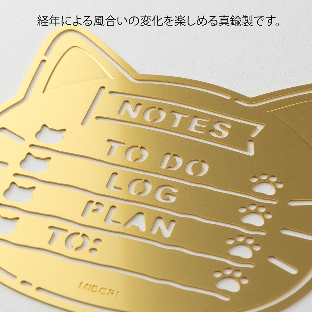 A slim brass stencil with cut-out cat faces, paw prints, and checklist boxes, designed for decorating planners, notebooks, and memos.