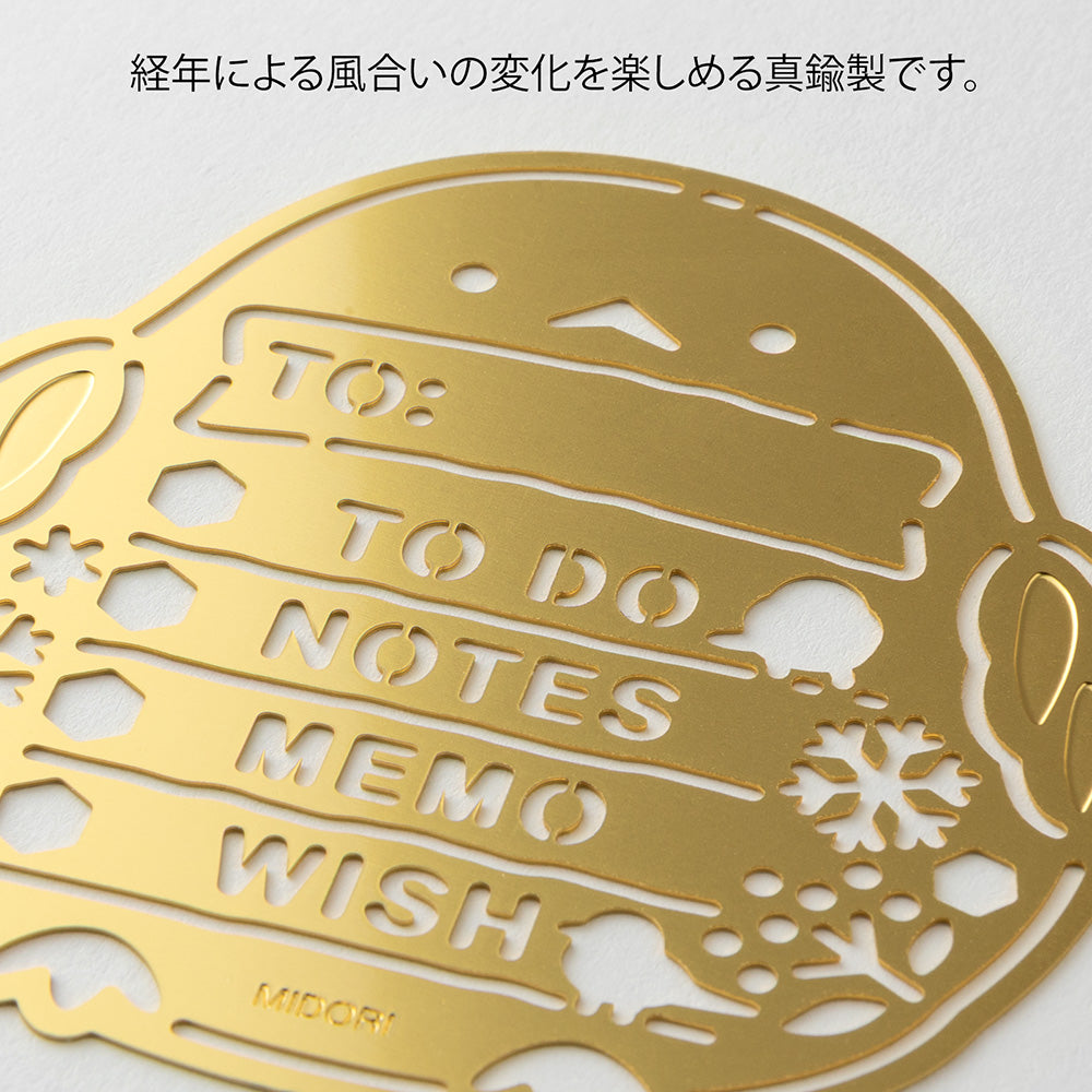 A slim brass stencil with cut-out illustrations of long-tailed tits, snowflakes, berries, and checklist boxes, designed for decorating planners, notebooks, and memos.