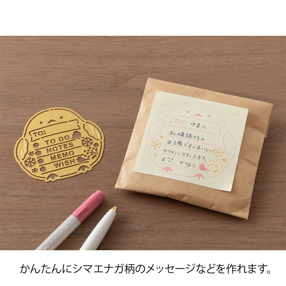 A slim brass stencil with cut-out illustrations of long-tailed tits, snowflakes, berries, and checklist boxes, designed for decorating planners, notebooks, and memos.