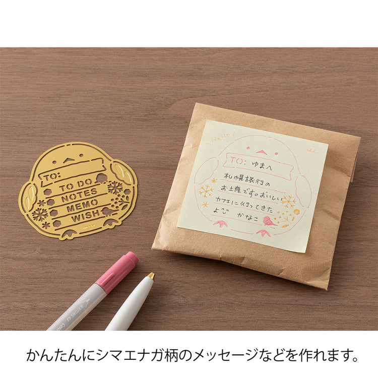 A slim brass stencil with cut-out illustrations of long-tailed tits, snowflakes, berries, and checklist boxes, designed for decorating planners, notebooks, and memos.