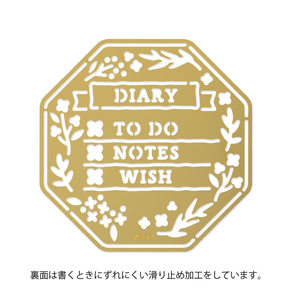 A brass stencil with floral and leafy cut-outs forming wreath-style designs, along with headings, to-do boxes, and animal details for decorating planners and memos.