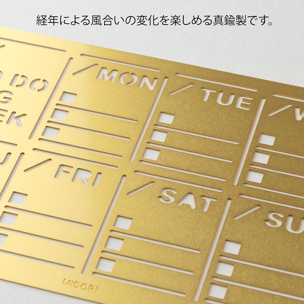 A slim brass stencil with a weekly block design, used for tracing neat weekly schedules, to-do lists, and daily records in notebooks.