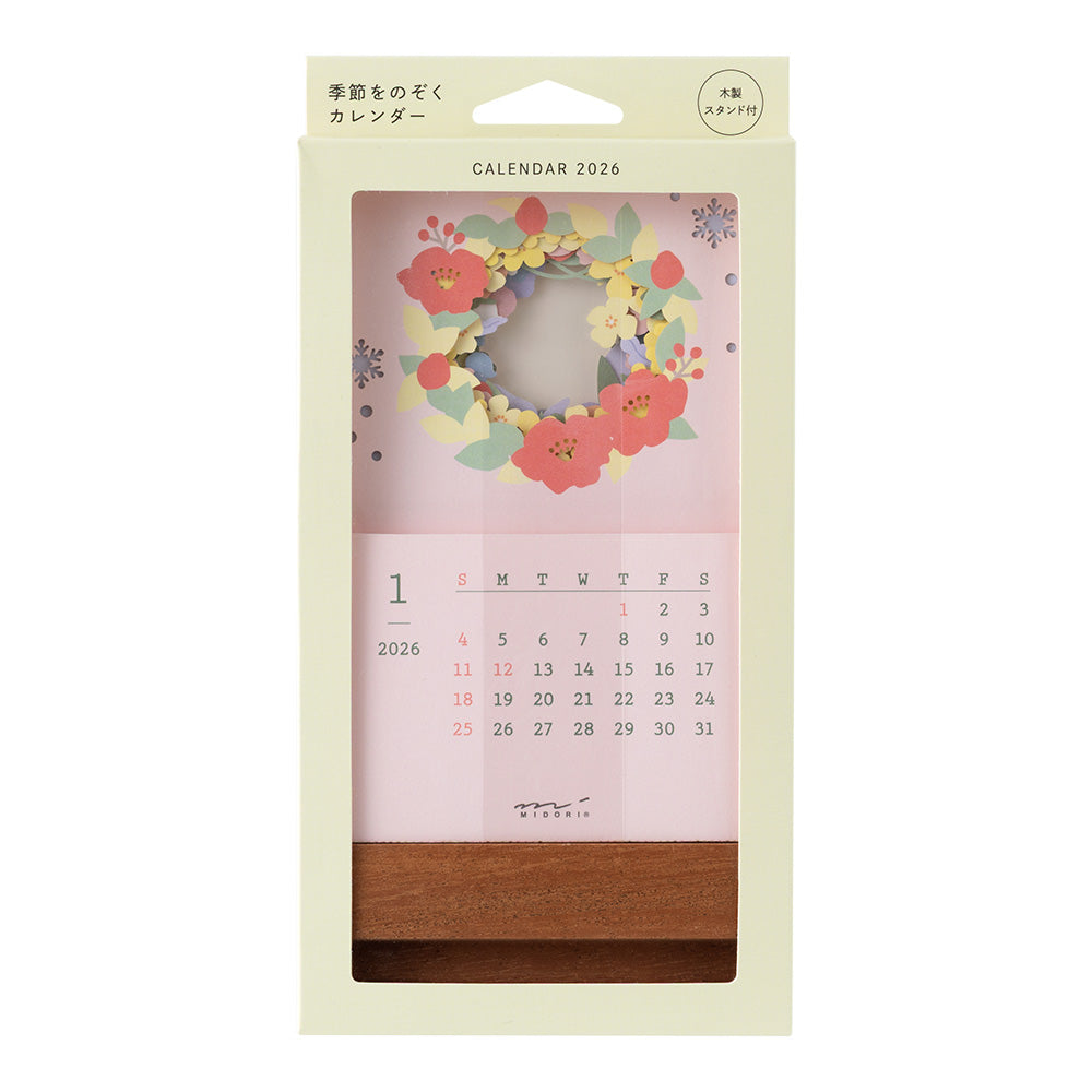 A delicate 2026 desktop calendar featuring layered, laser-cut floral designs that change with the seasons. Each month reveals a new arrangement of blossoms, displayed on a compact wooden stand, bringing an artful and elegant touch to any desk or small space.