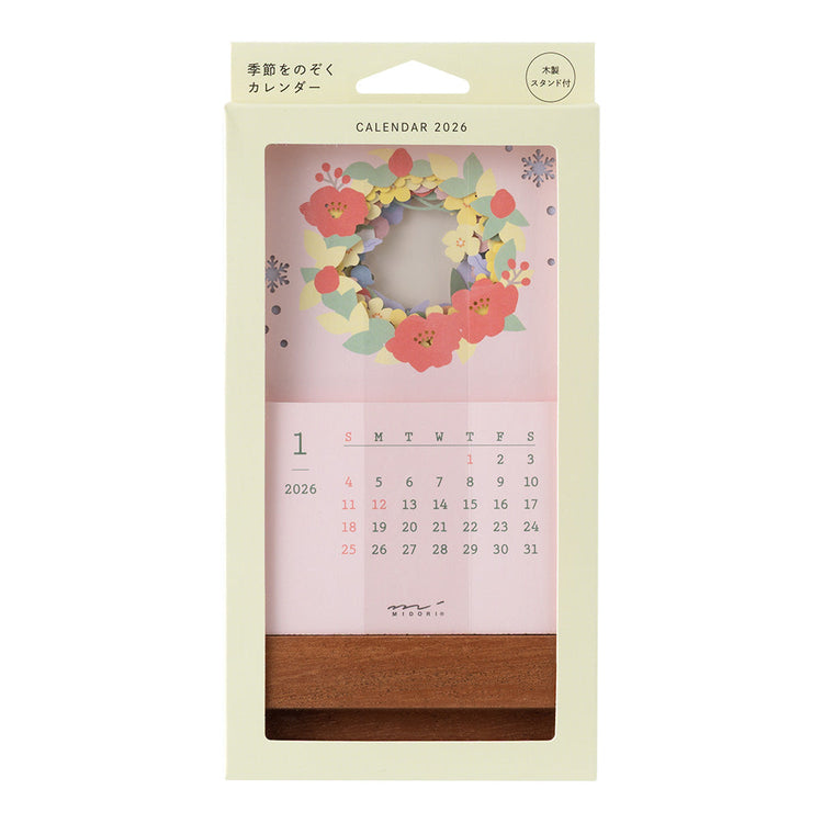 A delicate 2026 desktop calendar featuring layered, laser-cut floral designs that change with the seasons. Each month reveals a new arrangement of blossoms, displayed on a compact wooden stand, bringing an artful and elegant touch to any desk or small space.