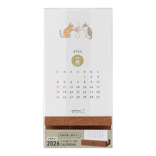 Midori Stand Calendar 2026 – Cat, a slim desktop calendar with a wooden stand, featuring soft, hand-drawn illustrations of cats by Sayo Koizumi in seasonal scenes.