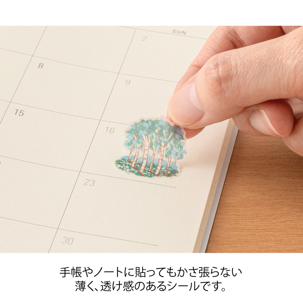 A sheet of Midori Finnish Motifs washi stickers by Yuuka Takamaru, with illustrations of reindeer, Nordic cottages, pine trees, berries, and folk embroidery patterns. The soft, pastel palette evokes the peaceful charm and traditions of Finland.